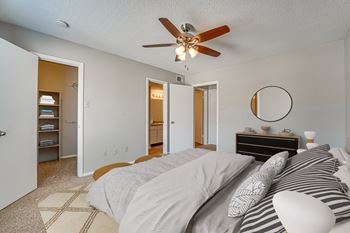 A bedroom with a bed, dresser, and a ceiling fan.